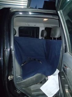 the inside of a car with its door open and blue seat covers folded up on it