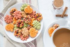 a white plate topped with lots of cookies next to a cup of coffee and cinnamon sticks