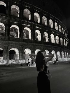 a woman standing in front of the colossion at night with her hands up