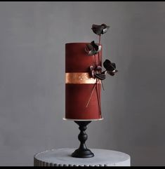 a three tiered red and gold wedding cake with flowers on the top, sitting on a pedestal