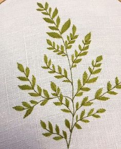 a close up of a embroidery on a piece of cloth with a plant in the middle