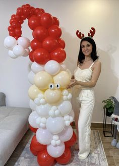 a woman standing next to a giant balloon arch with balloons in the shape of santa clause