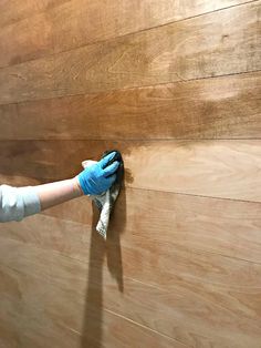 a person in blue gloves and white gloves is wiping up the wood wall with a rag