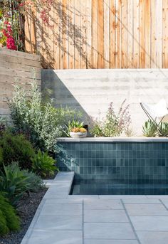 a small swimming pool surrounded by plants and flowers