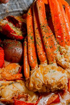 lobsters, crab legs and potatoes in a bowl with seasoning on the side