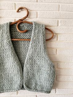 a knitted vest hanging on a brick wall