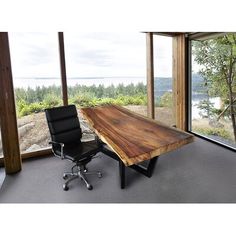 a wooden table sitting next to a black chair in front of a large glass window