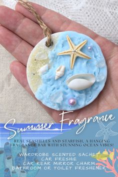 a hand holding a ceramic ornament with seashells and starfish on it