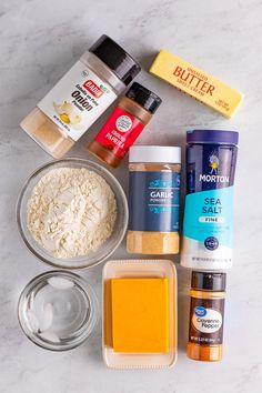 the ingredients to make this recipe are laid out on a marble counter top, including flour, butter, salt, and seasonings