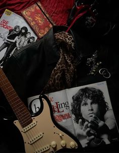 an electric guitar, magazine and other items on a bed