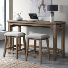 a wooden desk with two stools and a laptop on top of it in front of a window