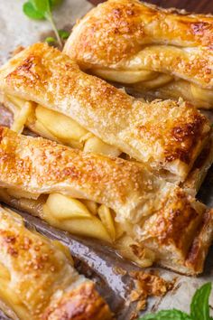 several pieces of apple pie sitting on top of a cutting board next to green leaves