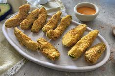 some fried food on a white plate next to an avocado and dipping sauce