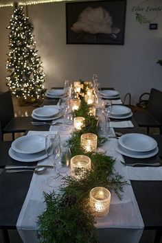 a long table is set with candles and greenery on it for dinner guests to enjoy