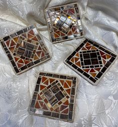 three decorative glass coasters sitting on top of a white cloth