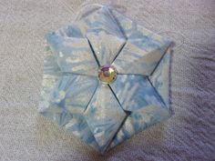 an origami flower is sitting on top of a tablecloth covered surface with blue and white designs