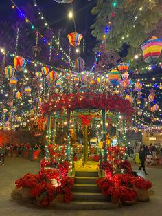 an elaborately decorated gazebo surrounded by christmas lights and garlands at night time