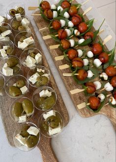 several appetizers are lined up on a wooden platter with toothpicks and olives