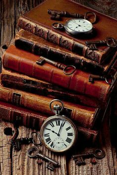 an old pocket watch sitting on top of three books with keys and keychains