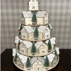 a wooden christmas tree with numbered houses and trees on the top, in front of a checkered wall