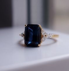 a close up of a ring with a blue stone and two white stones on it