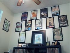 there is a wall full of movie posters and movies on the wall, with a ceiling fan in front of it