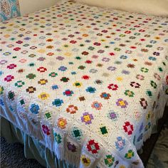 a white crocheted bedspread with multicolored flowers and fringes