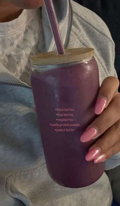 a woman holding a purple cup with a straw in her hand and the words on it