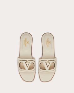 Valentino Garavani VLogo cut-out slide sandal in calfskin leather - VLogo Signature cut-out calfskin detail with mirror-effect trim - Insole with padded heel for extra comfort - Heel height: 5 mm / 0.2 in. - Made in Italy Luxury Slides With Branded Insole And Open Heel, White Luxury Calf Leather Mules, Luxury White Calf Leather Mules, Luxury Beige Slip-on Sandals, Elegant Flat Calf Leather Slides, Luxury Flat Mules With Leather Lining, Calf Leather Open Toe Slides, Elegant Beige Leather Slides, Luxury Cream Mules