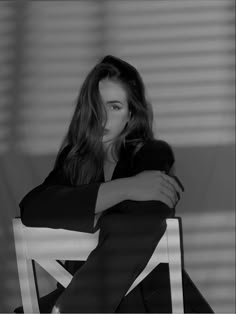 a black and white photo of a woman sitting in a chair with her arms crossed