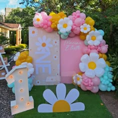 an outdoor area with flowers and balloons on the grass, including one sign that says 1