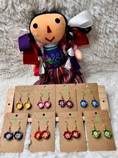 a stuffed animal sitting next to several pairs of earrings