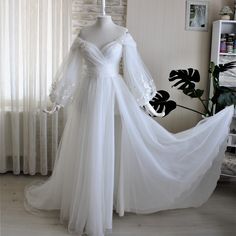 a white wedding dress on display in front of a brick wall with curtains behind it