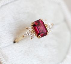 a close up of a ring with a red stone in it on a white cloth