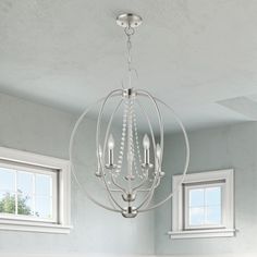 a chandelier hanging from the ceiling in a room with white walls and windows