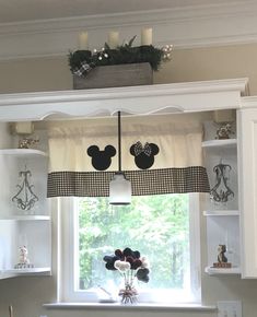 a kitchen window with mickey mouse decorations on the valance and shelf above it,