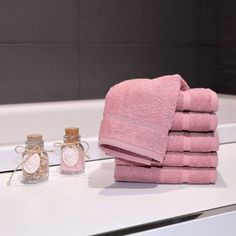 a stack of pink towels sitting on top of a bathroom counter