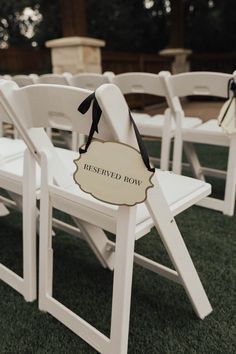 rows of white folding chairs with black bows and reserved row sign on the seat back