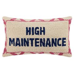 a pillow with the words high maintenance on it, and an embroidered design in blue