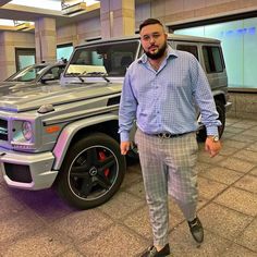 a man is standing in front of a mercedes benz g - class suv at an auto show