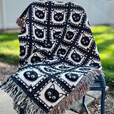 a black and white cat afghan sitting on top of a blue chair in the grass