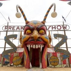 an elaborately painted mask is displayed in front of a sign that says freakshow