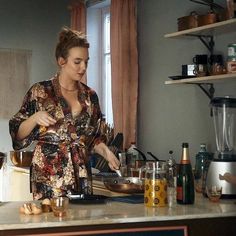 a woman standing in a kitchen preparing food on top of a counter next to a window