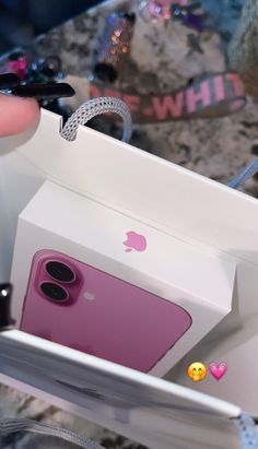 a person holding an iphone in a white box with embellishments on it