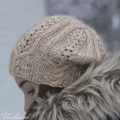 a woman wearing a knitted hat with fur on it's back and her hair in the wind