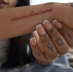 a woman holding her arm with the word divine feminine written on it in red ink