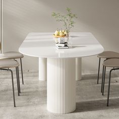 a white table with chairs around it and a vase filled with fruit on the top