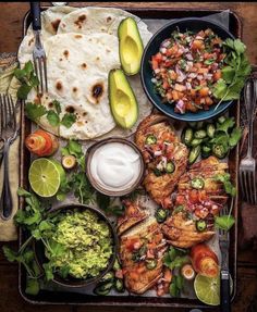 a tray filled with tacos, guacamole, and other food items