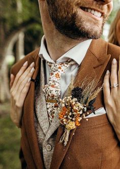 a man in a suit and tie with flowers on his lapel