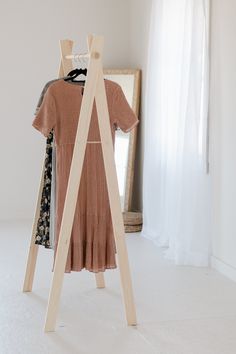 a dress hanging on a clothes rack in front of a white wall with a mirror